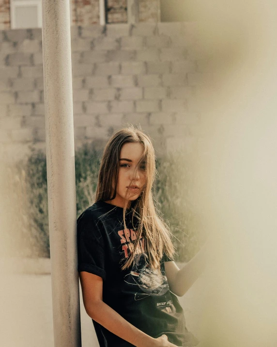 a young woman is standing by the side of a pole