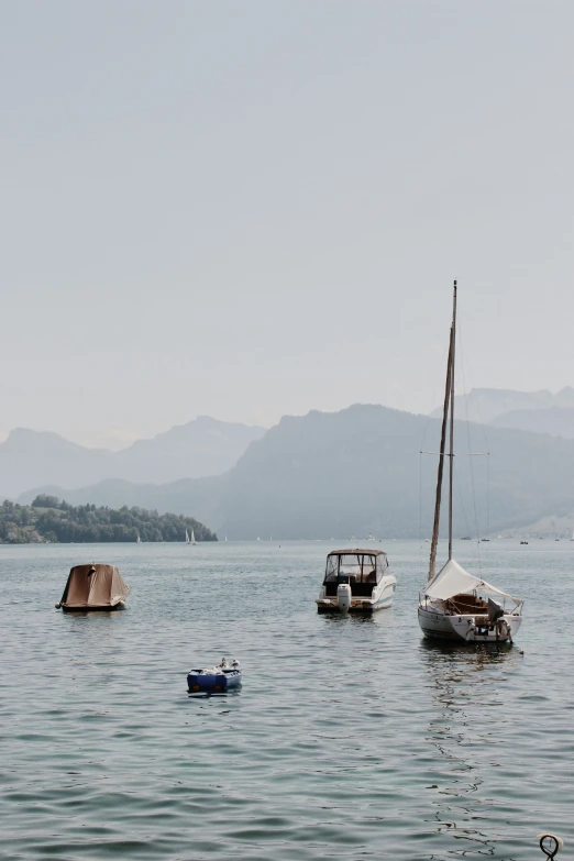 several boats sailing in the water with mountains in the background