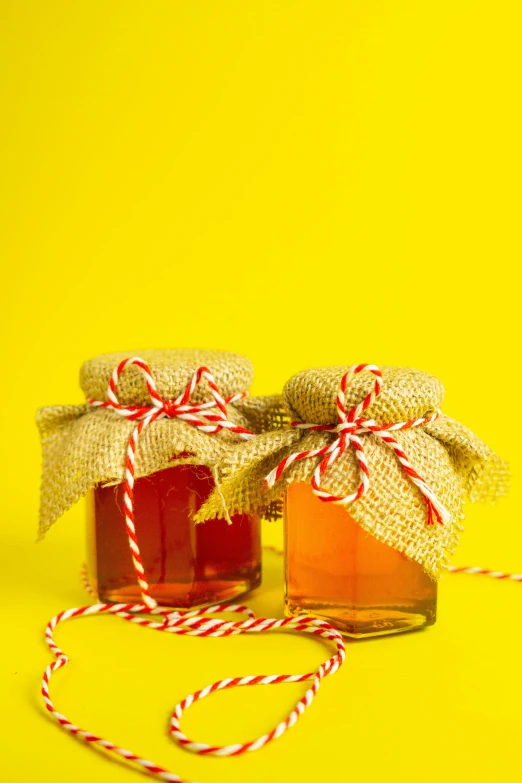 a jar of syrup and two pieces of candy canes on a yellow background