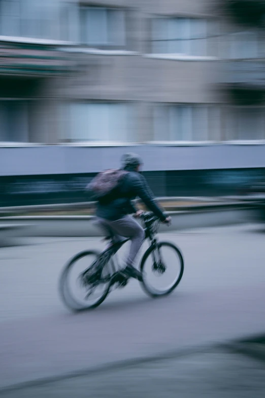 a blurry po of a bicyclist moving along the street