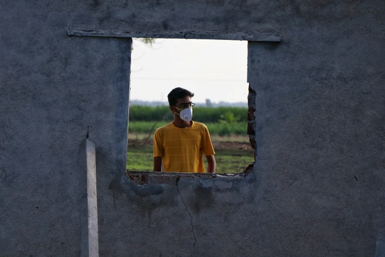 a man wearing a mask looking out a window