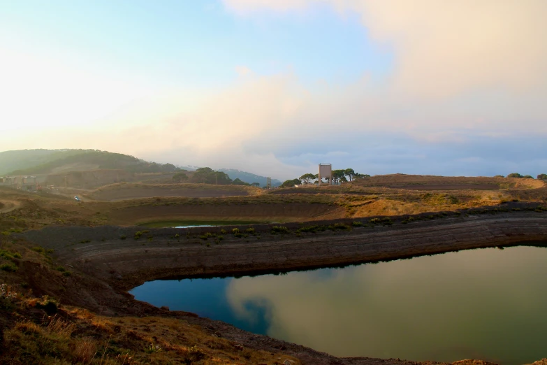 a mountain that has a pond and some bushes