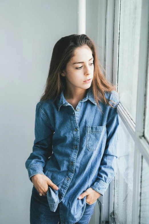 a woman stands on stairs, wearing denim shirts