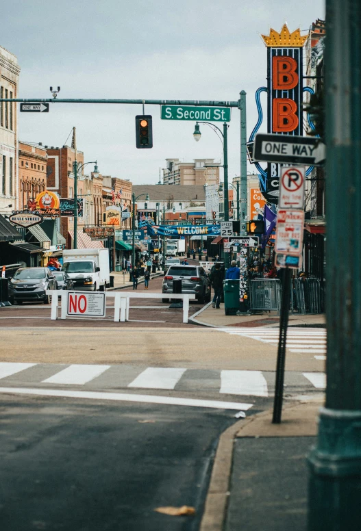 an intersection is seen under street signs on a cloudy day