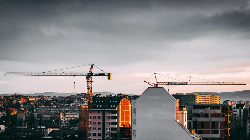 three cranes are against an overcast sky