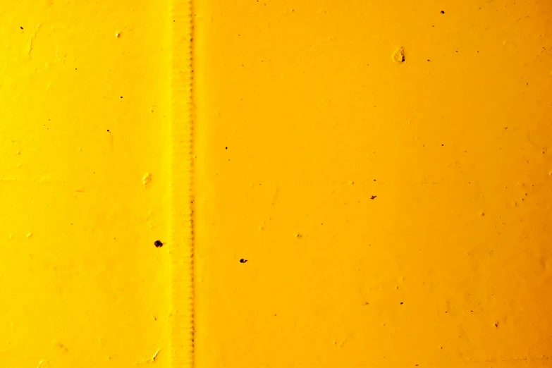 the side of a yellow wall with rusted rivets