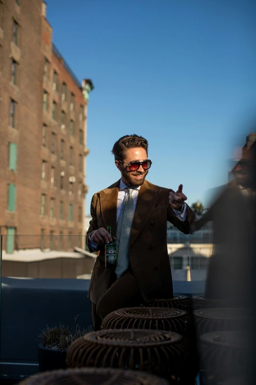 man sitting on top of a car in a suit