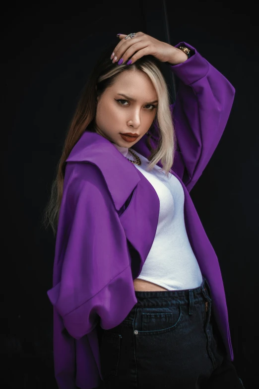 a woman wearing purple is standing in front of a black background