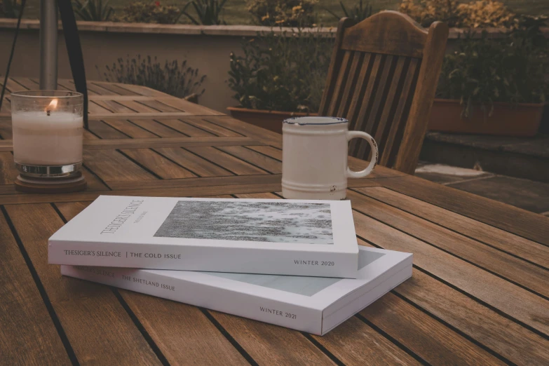 two books on the outside table with a candle