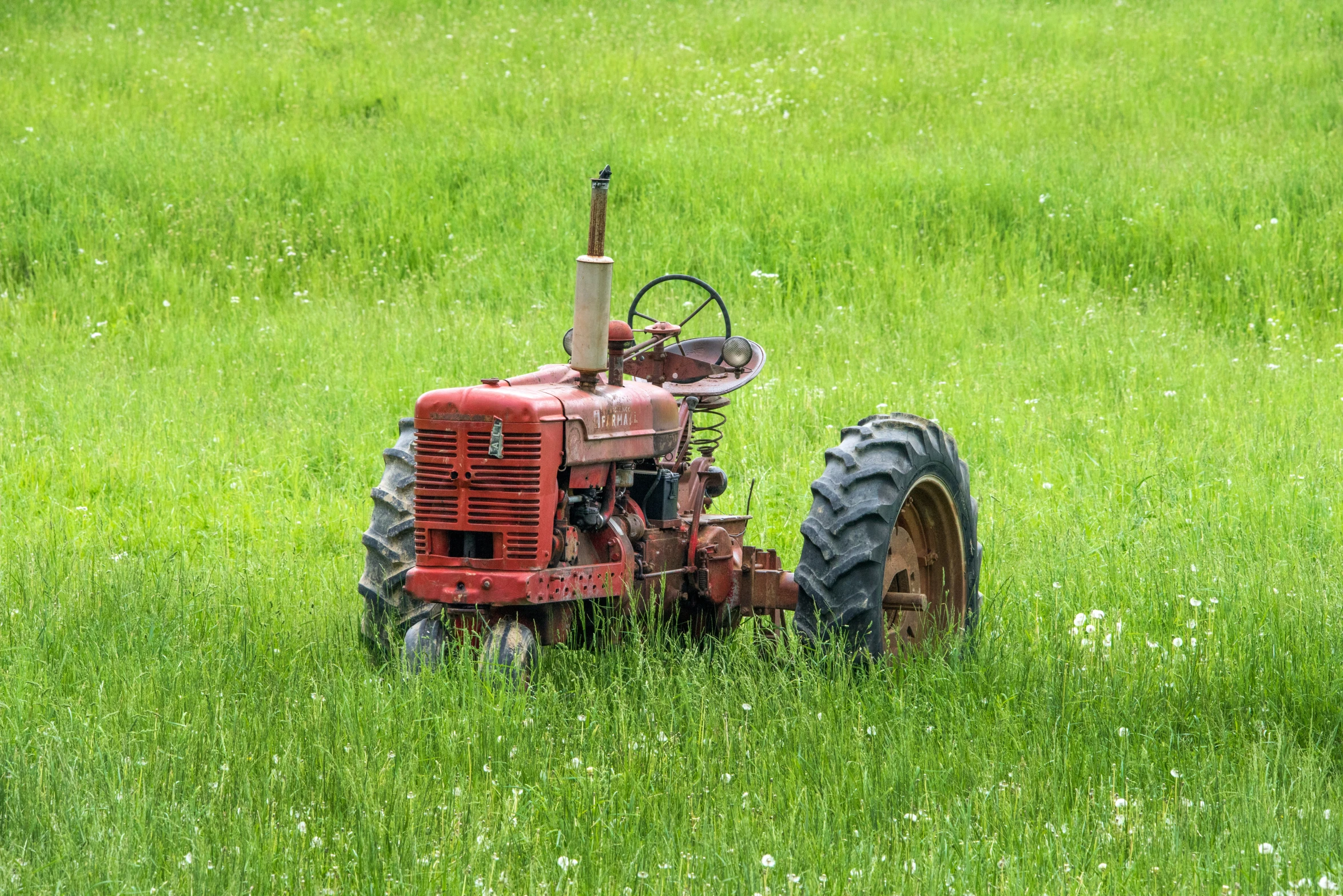 a large red tractor sitting in a field of grass