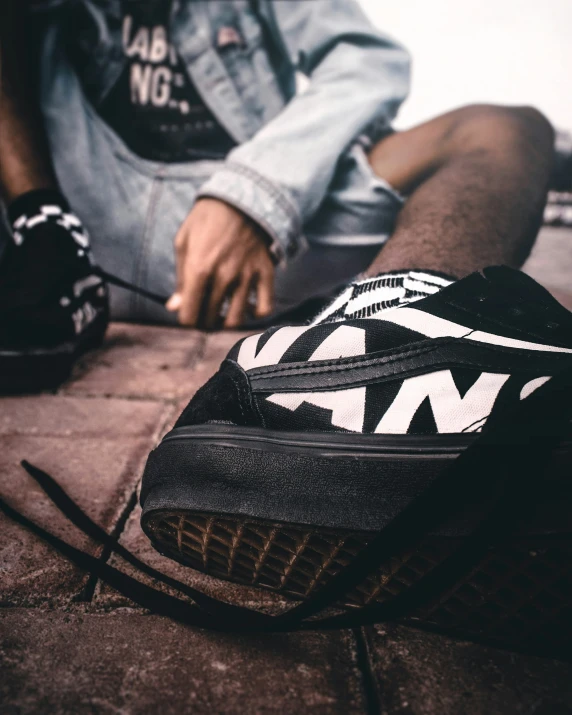 a man sits on the ground tying his vans shoes
