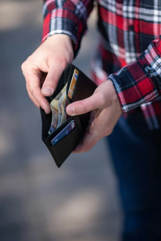 a man in a red and black shirt holding a black wallet