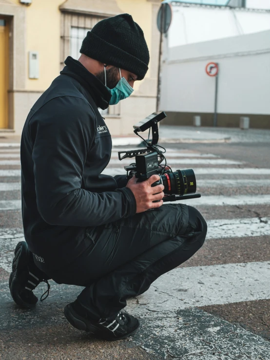 a man is kneeling down while holding a video camera