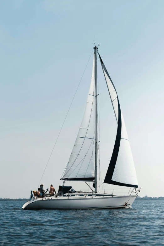 white sailboat with two people on the front and a full view of back