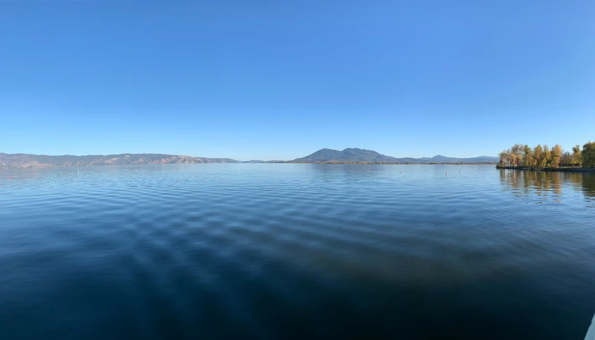 a body of water with trees and mountains in the background