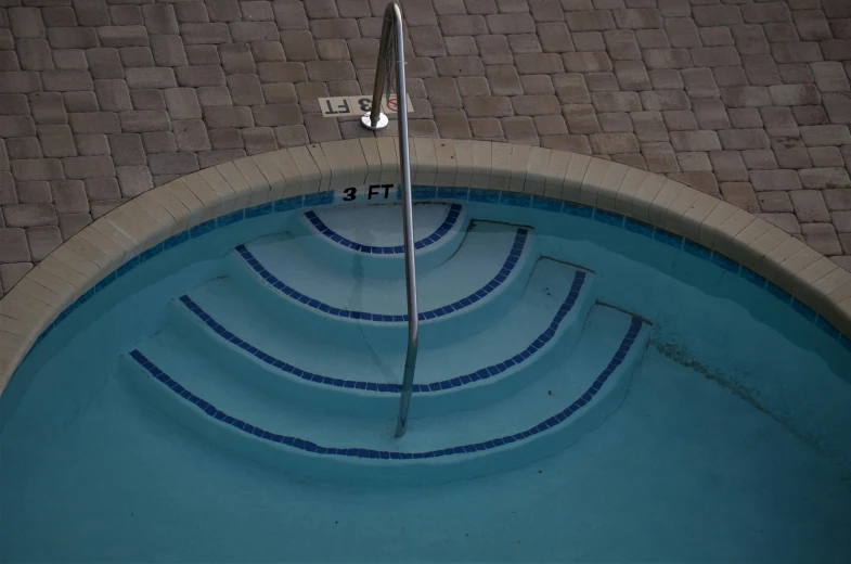 the concrete steps lead to the edge of an empty swimming pool