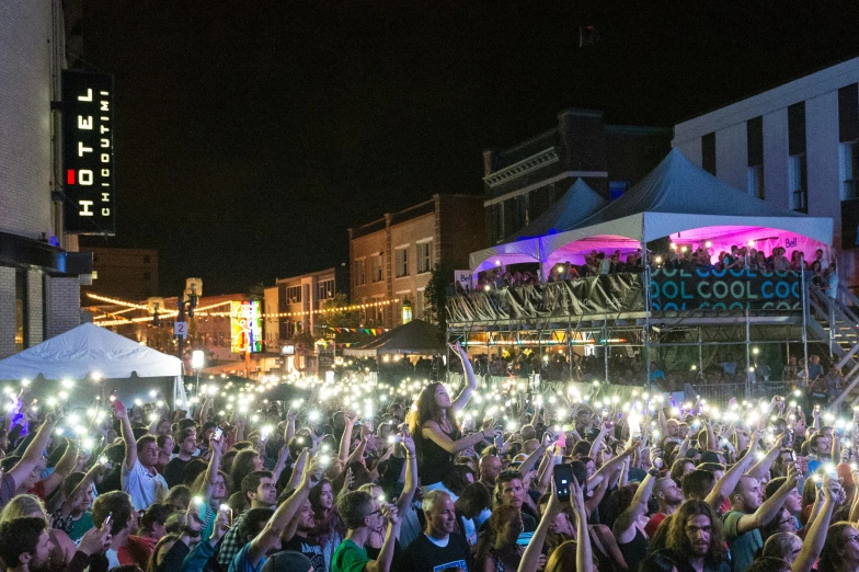 a large crowd in the middle of a city street holding their hands up