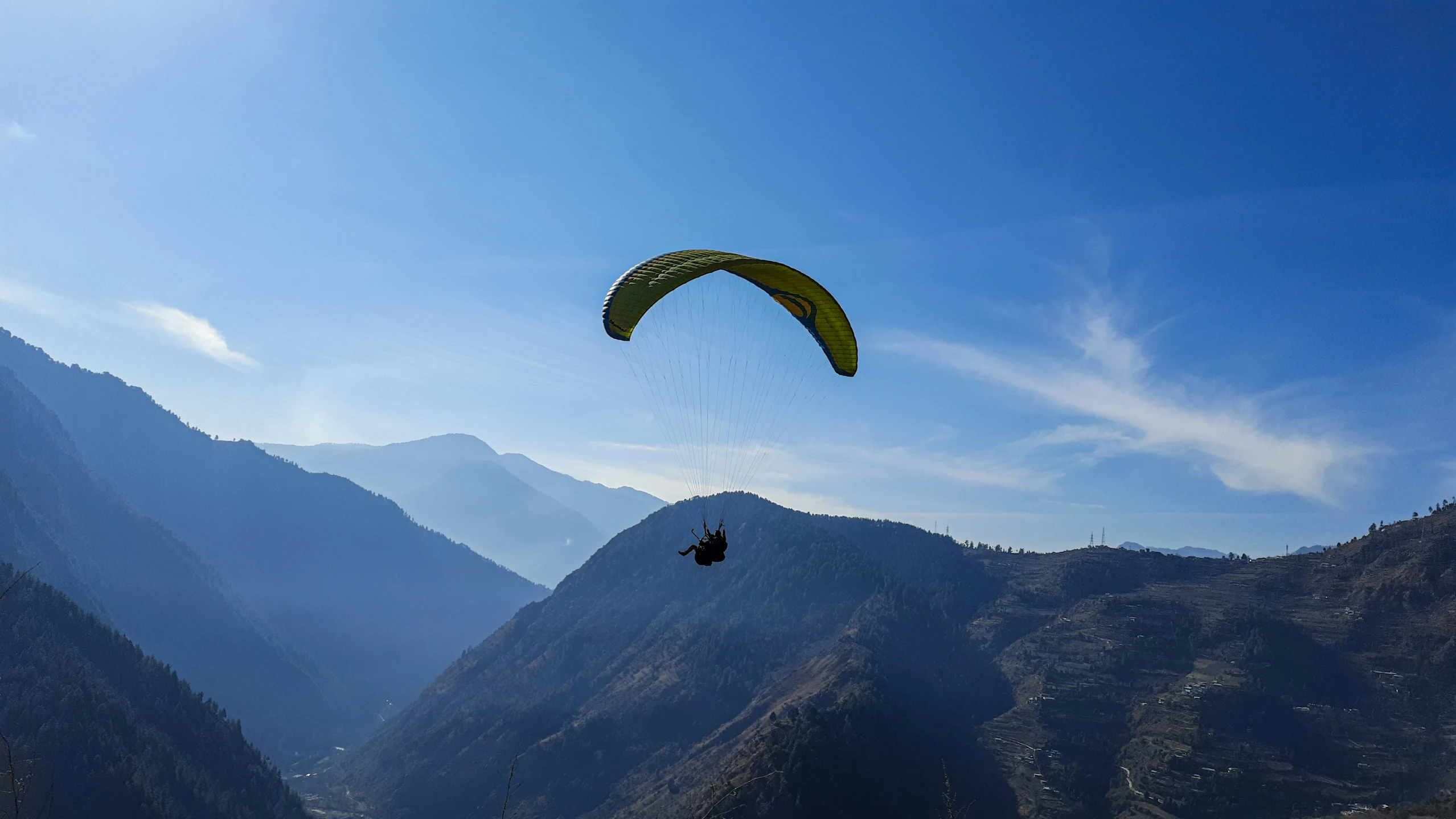 paraglider gliding in the mountains above a valley