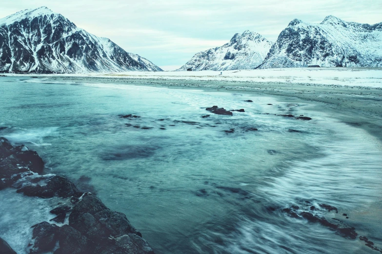 two snow covered mountains and the water in front of it