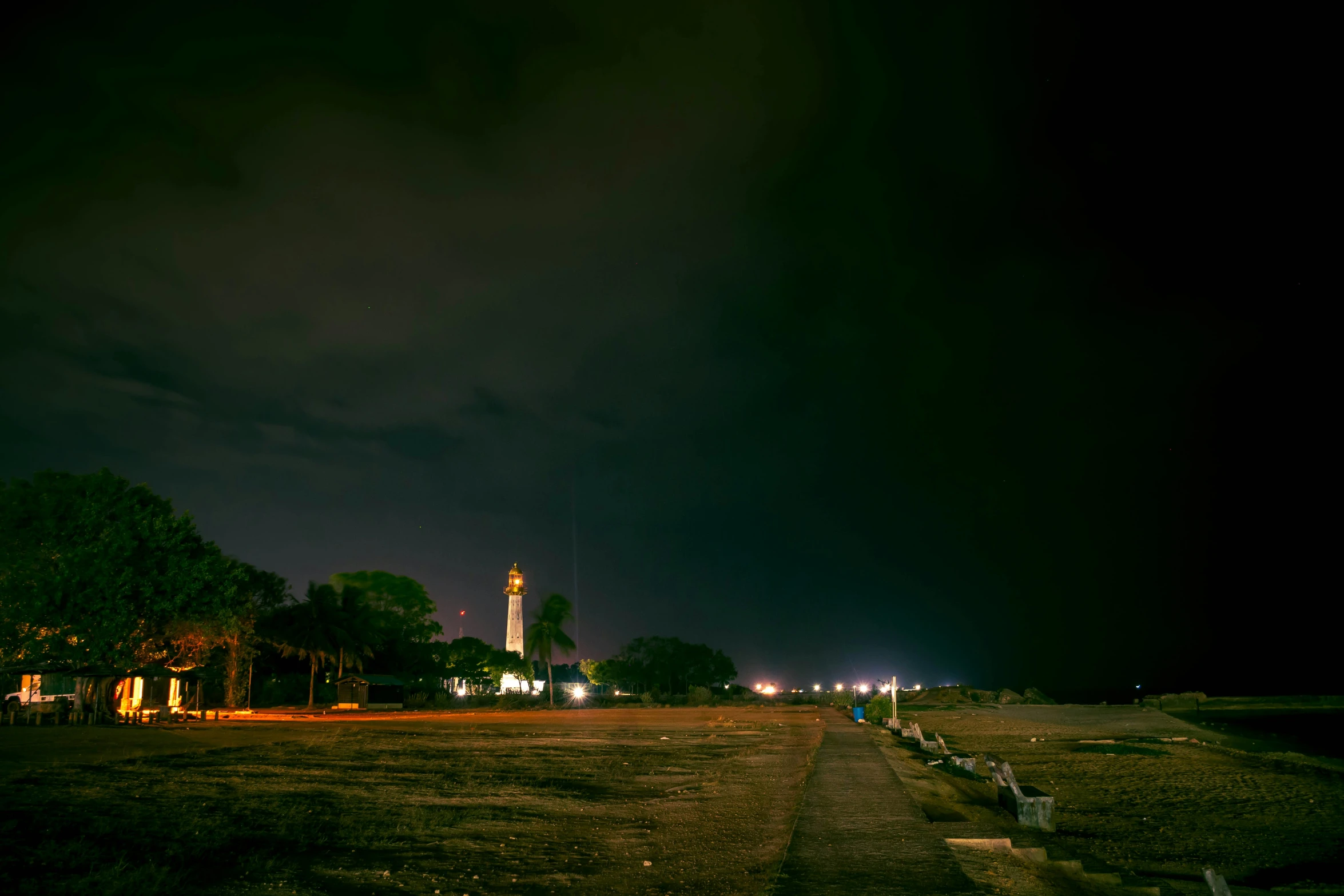 a long, empty street that is surrounded by dark clouds