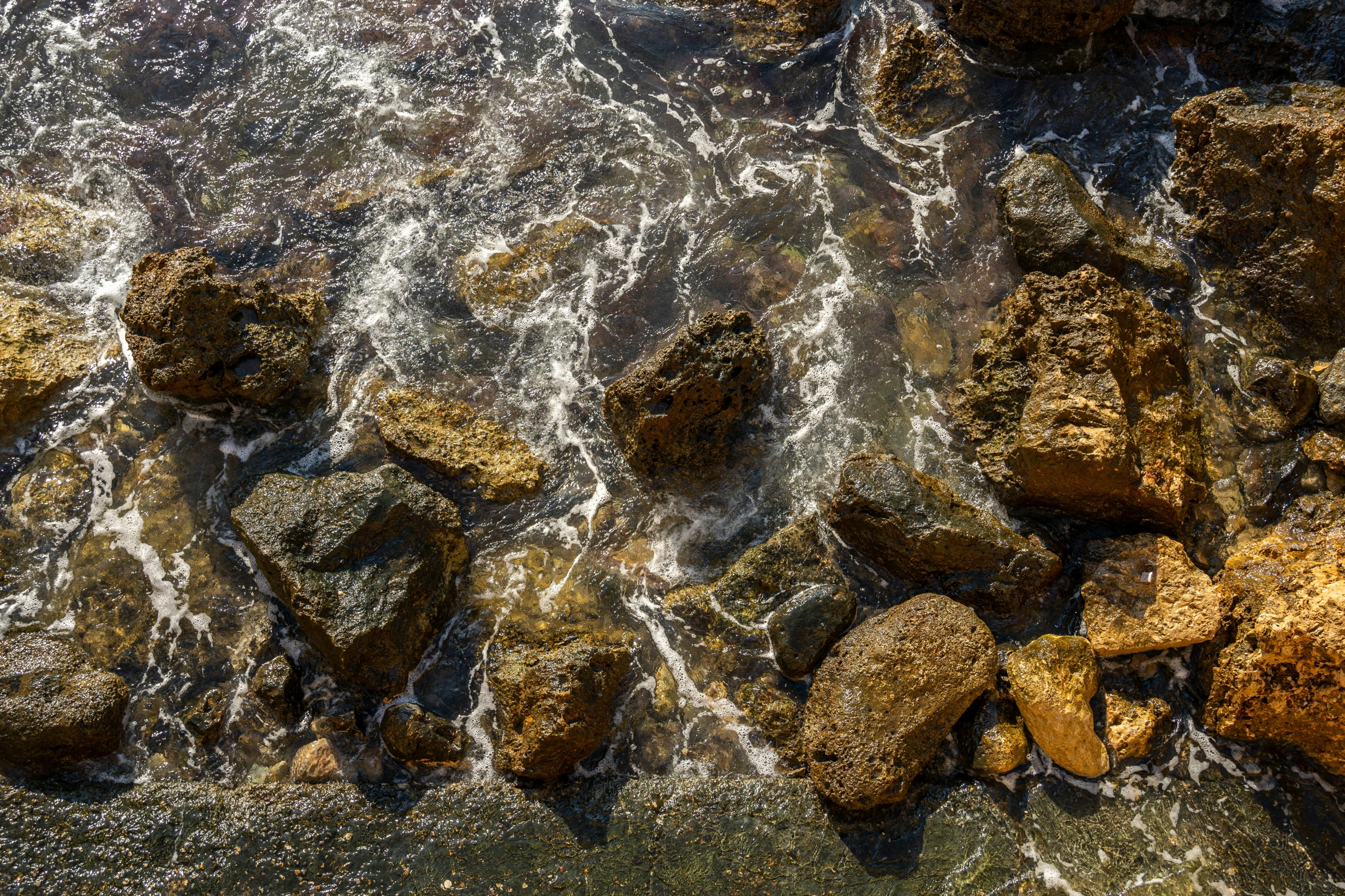 large rocks next to the water, under a plane