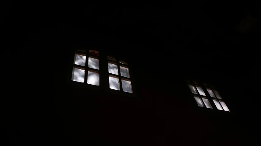 three different square windows lit up in a dark room