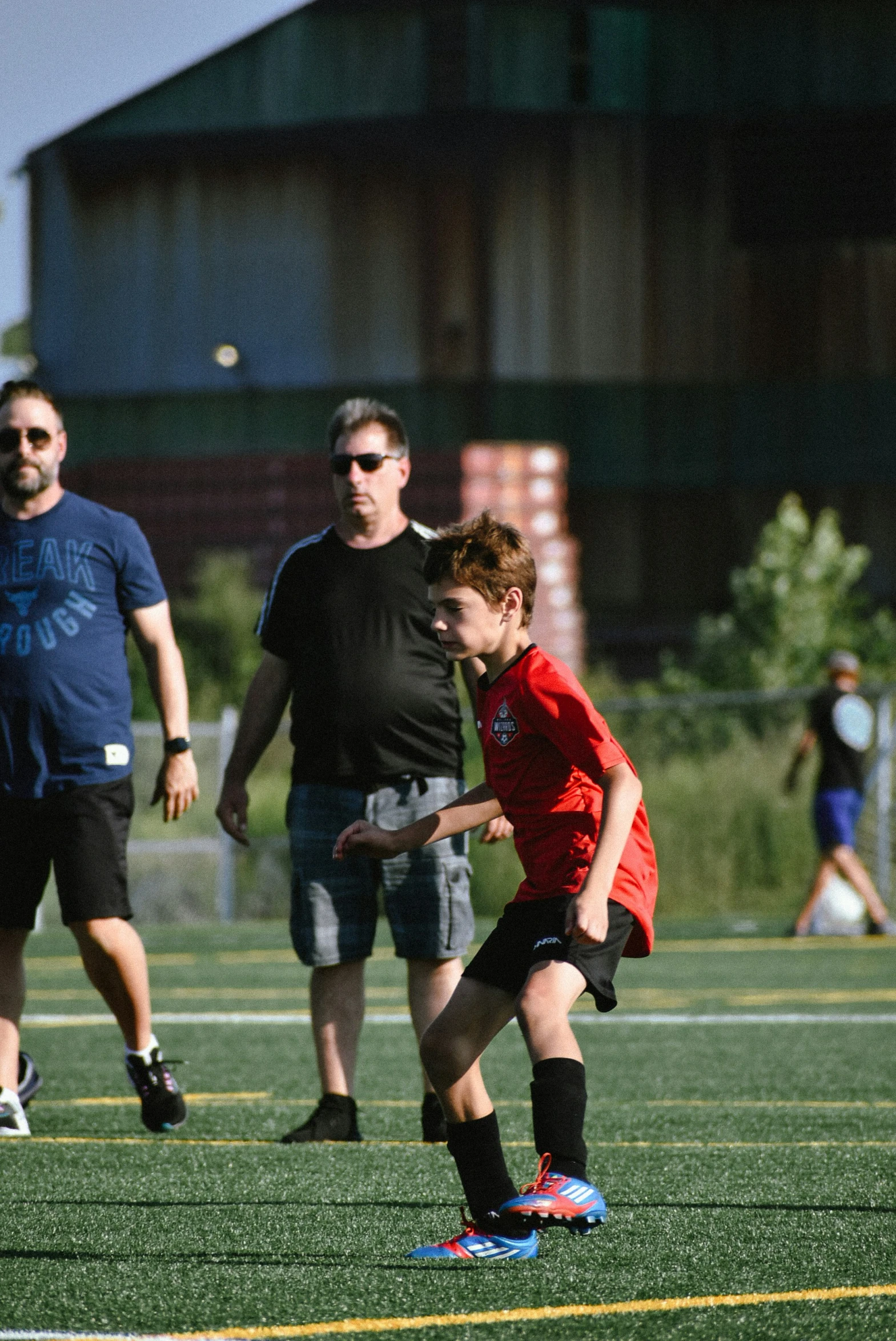 the young child is playing soccer with the parents