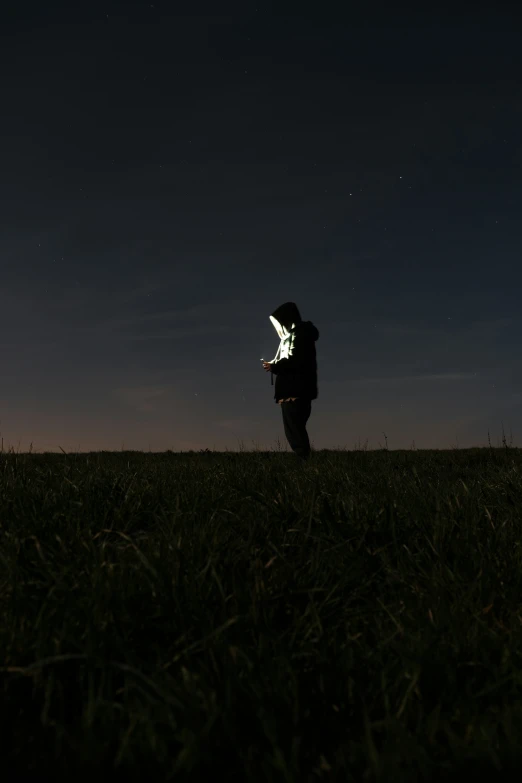 the man is standing in the field while holding a kite