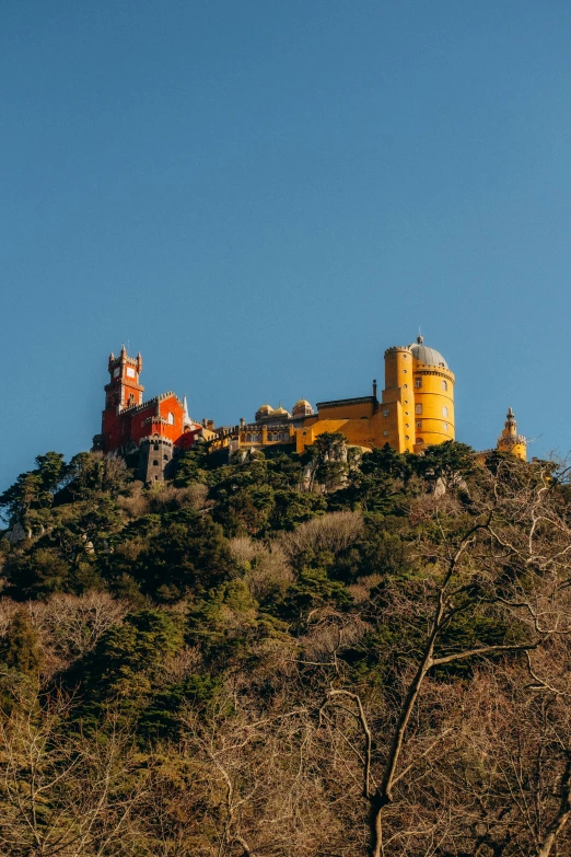 a castle atop a green mountain under a blue sky