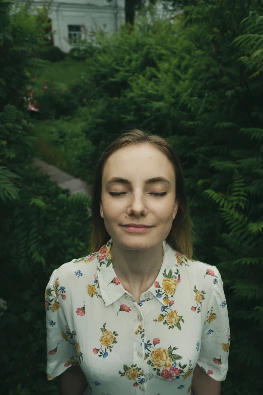 a woman standing in front of trees and bushes