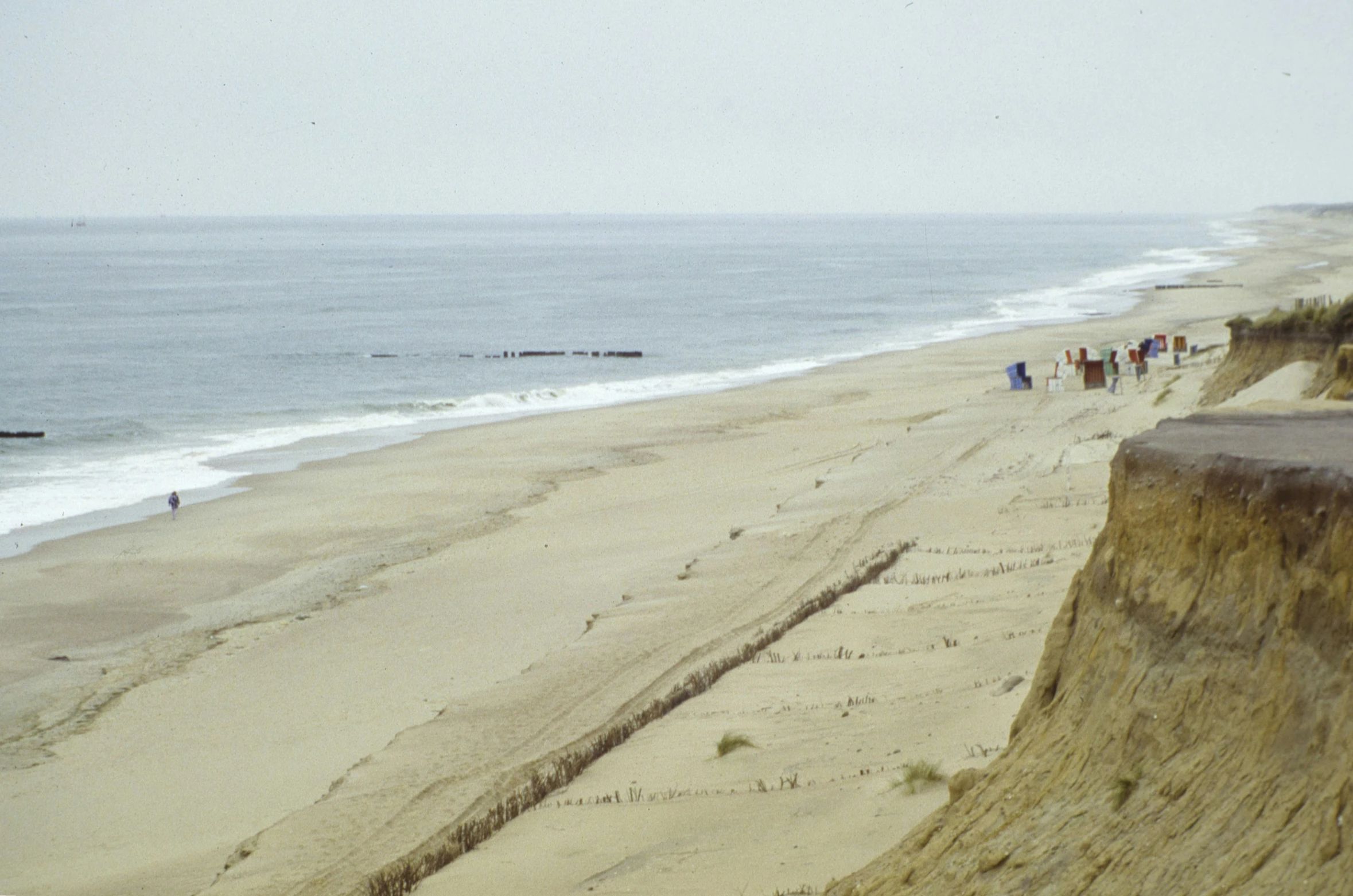 people walk on the sand at the edge of a beach