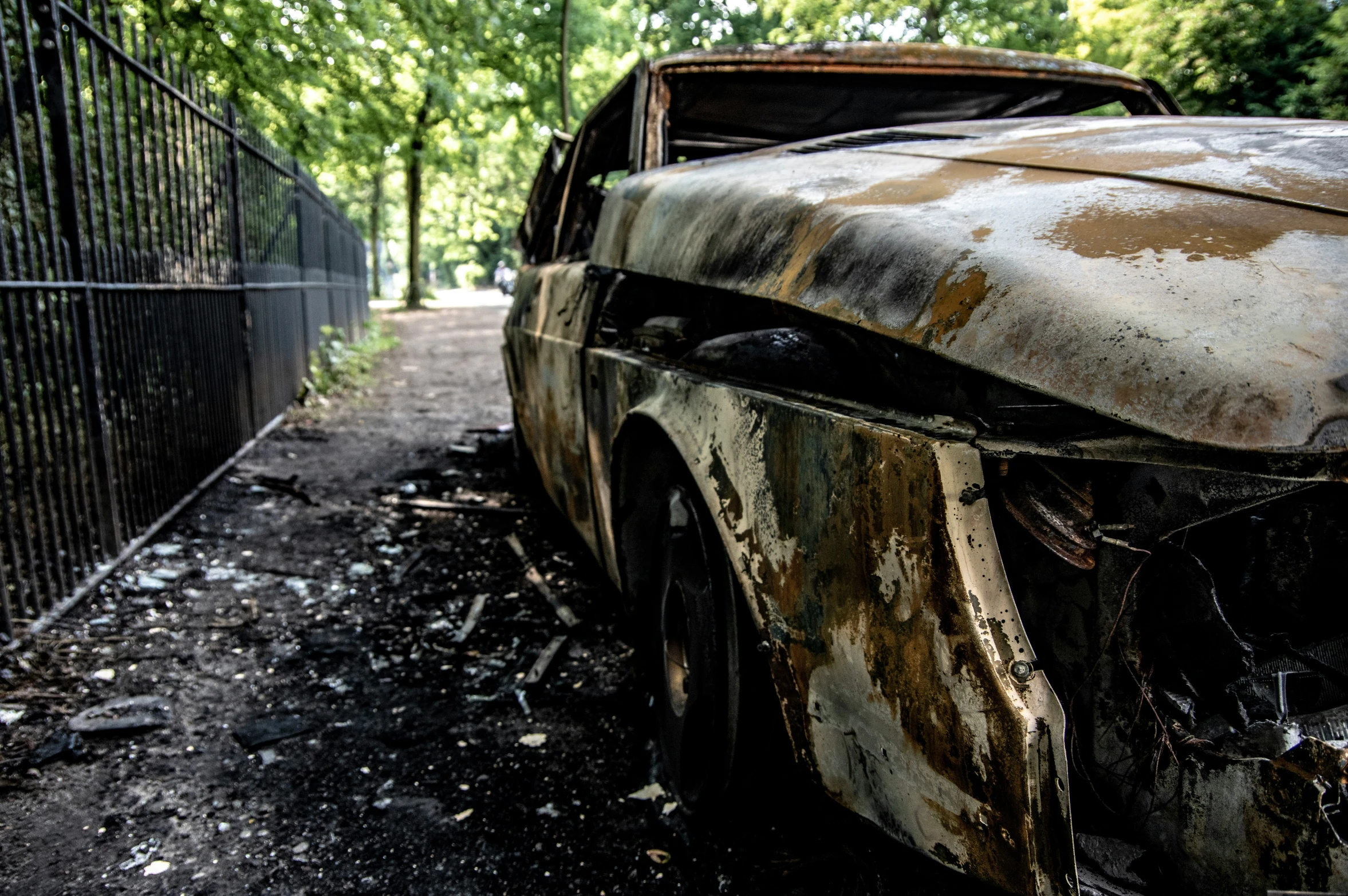 this rusty car is left on the dirt road