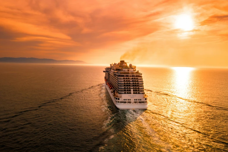 a large cruise ship is sailing across the ocean at sunset