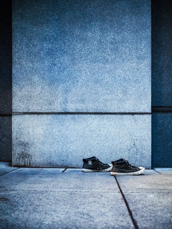 two shoes sitting outside on the sidewalk next to a building