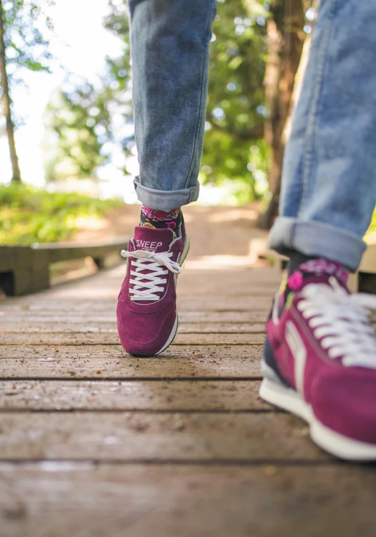 the person is walking down the boardwalk with their purple shoes on