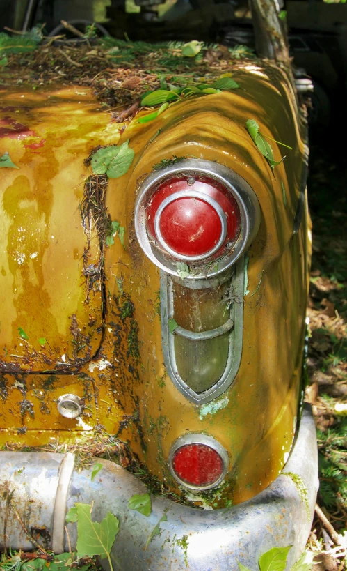 an old rusted yellow truck sitting in the dirt