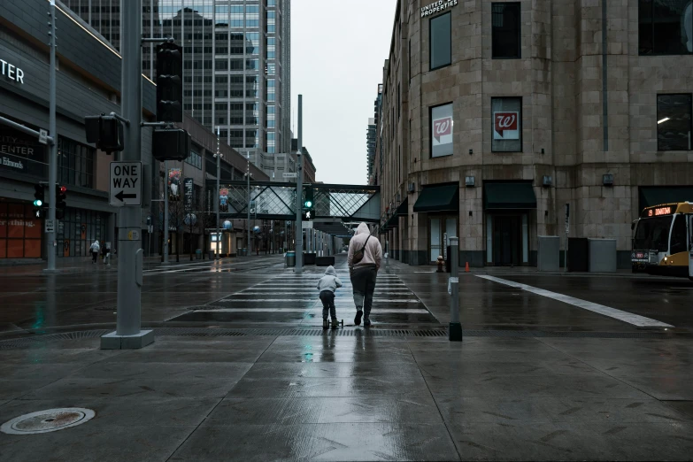 a man and woman with an umbrella cross a street in the rain