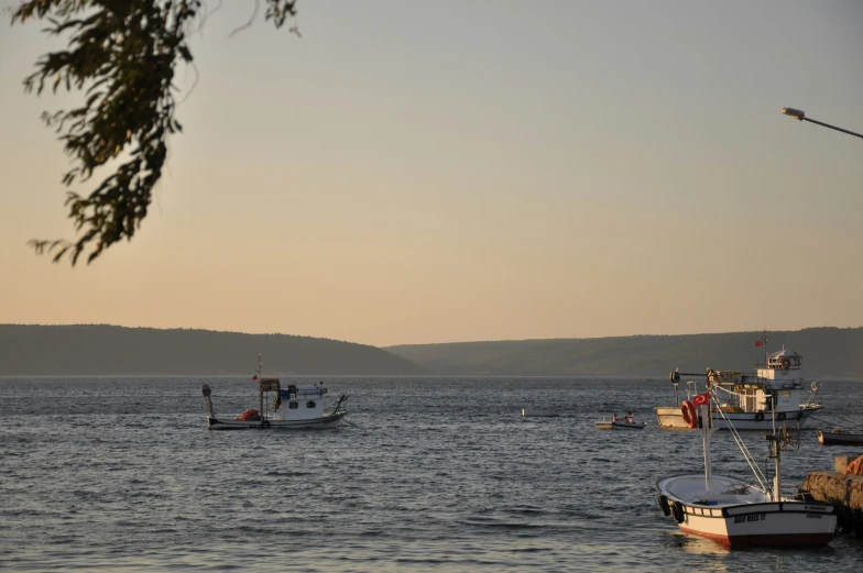 boats floating on the water at dusk in a lake