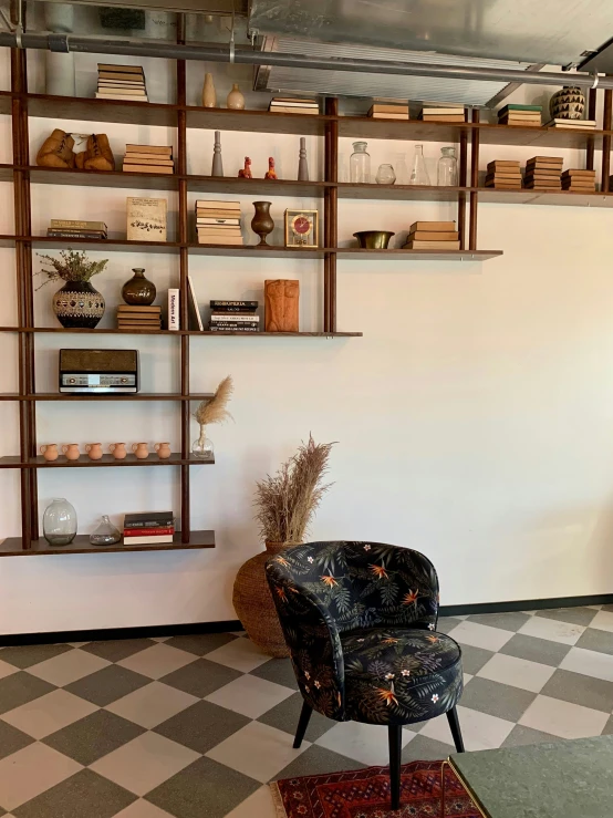 the corner of a room with two chairs, a rug and shelves