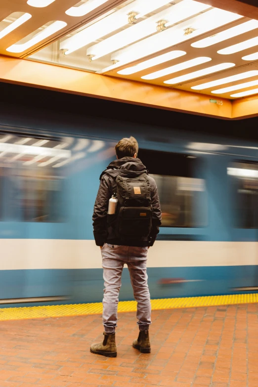 a man is standing on a subway platform looking at a train