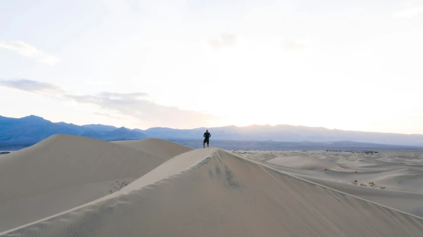 someone stands on top of a large hill of sand