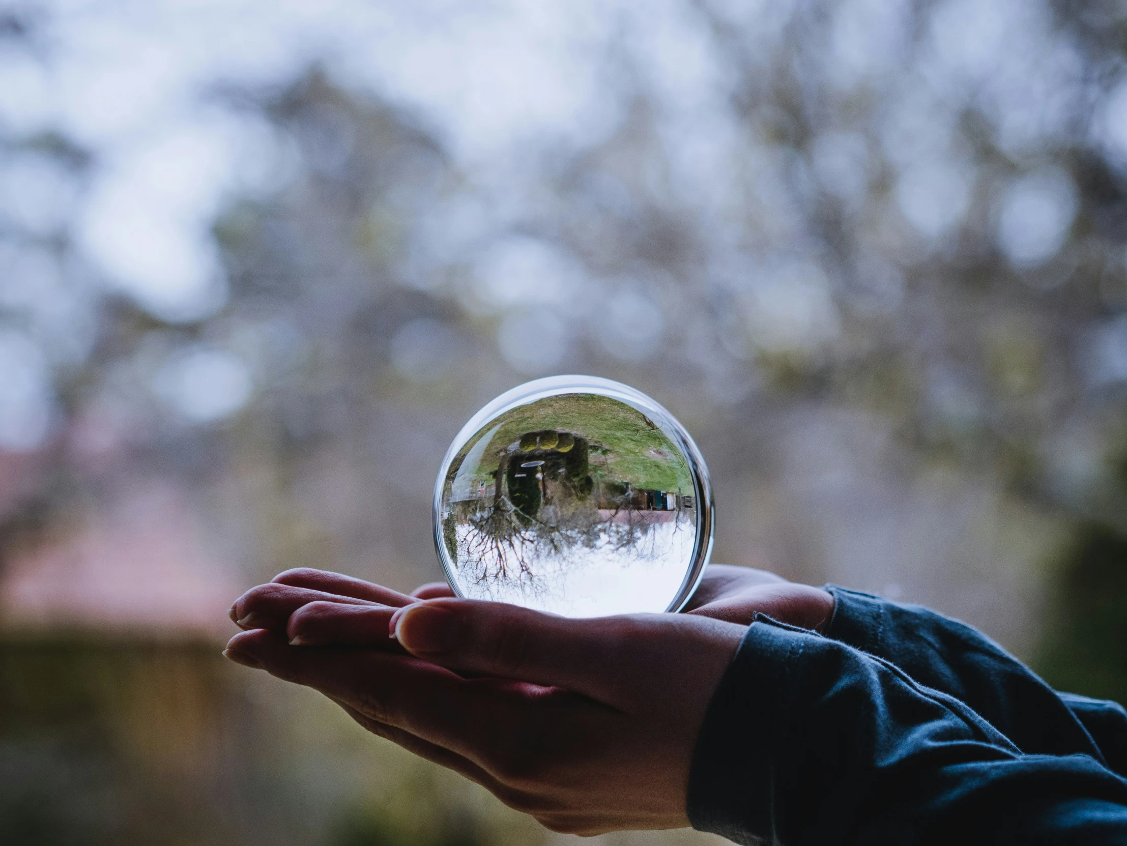 someone holds a large crystal ball in their palm