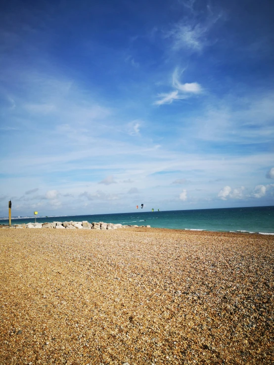 a view of the ocean with people walking and playing in the sand