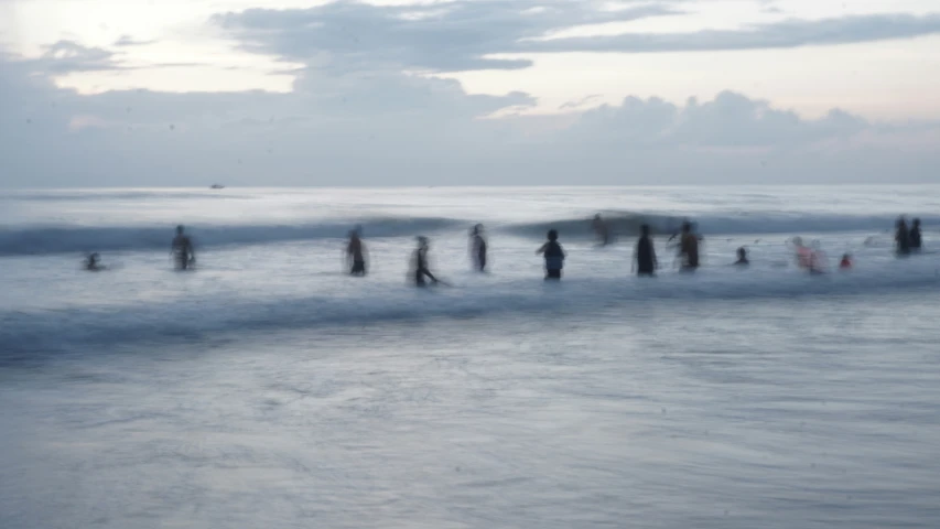 a long line of people with surfboards are on the ocean