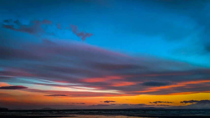 a sunset on the beach with some clouds in the sky