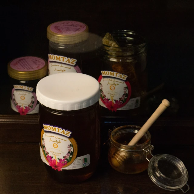 a jar of honey sitting on a table next to a container of honey