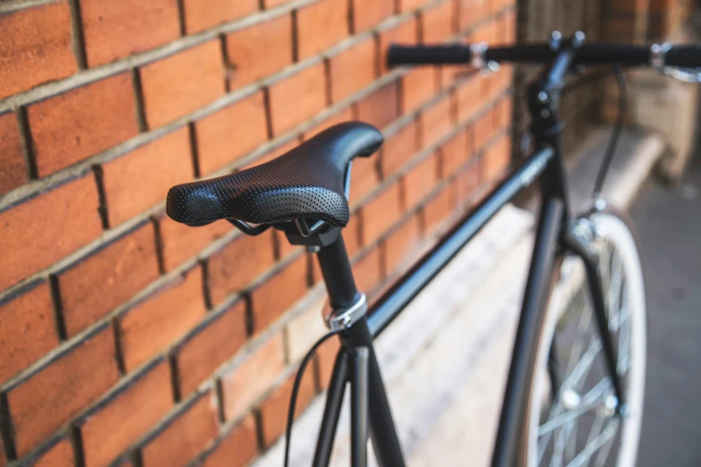 a bicycle parked next to a brick wall