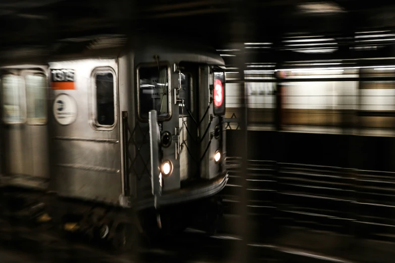 a silver train passing through an empty subway station