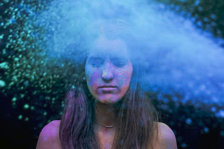 a woman standing beneath mist and the light is reflecting off her face