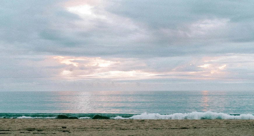 beach with waves crashing on sand and sky